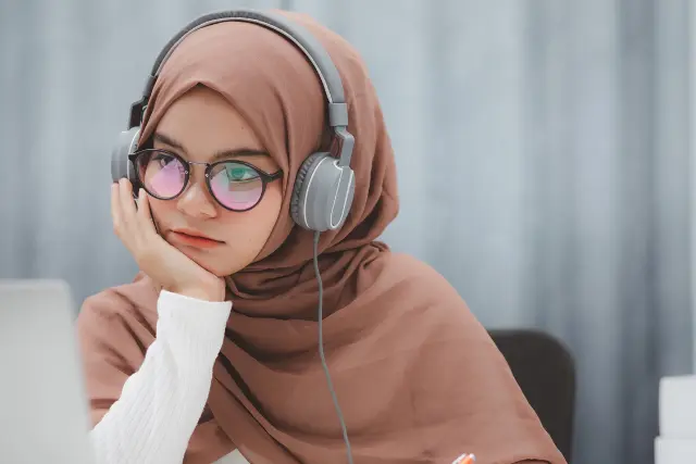 Young Muslim woman attending live online Quran class with Tajweed on laptop in USA and UK